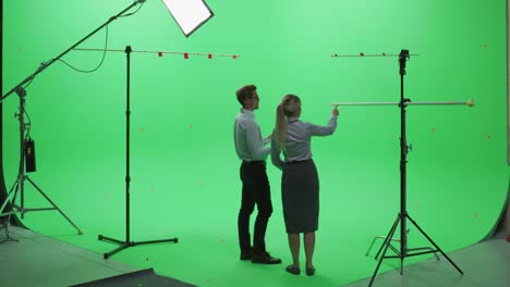 female and male colleagues wearing casual clothes, standing with their backs - using laptop computer in green screen mock up chroma key studio. business, corporate office, work, technology concept.