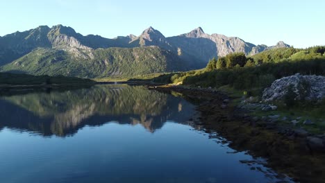 Drone-soars-over-fjord-waters-with-mountain-reflections