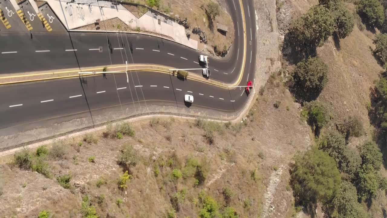 coches circulando por una carretera con curvas en una zona tropical, vista vertical aérea