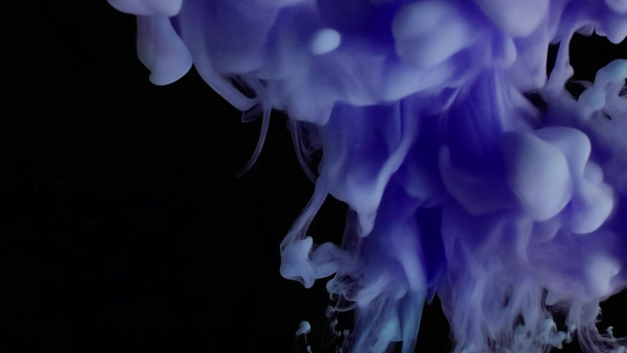 Inchiostro viola che gocciola e forma spirali nell'acqua su sfondo nero