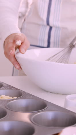 woman putting dough in muffin mold