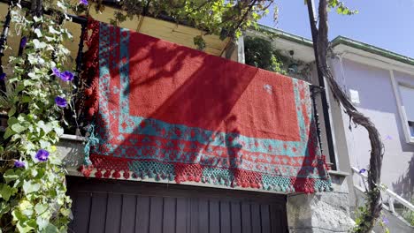 parallax around vibrant red grey rug hanging over railway adorned with flowers