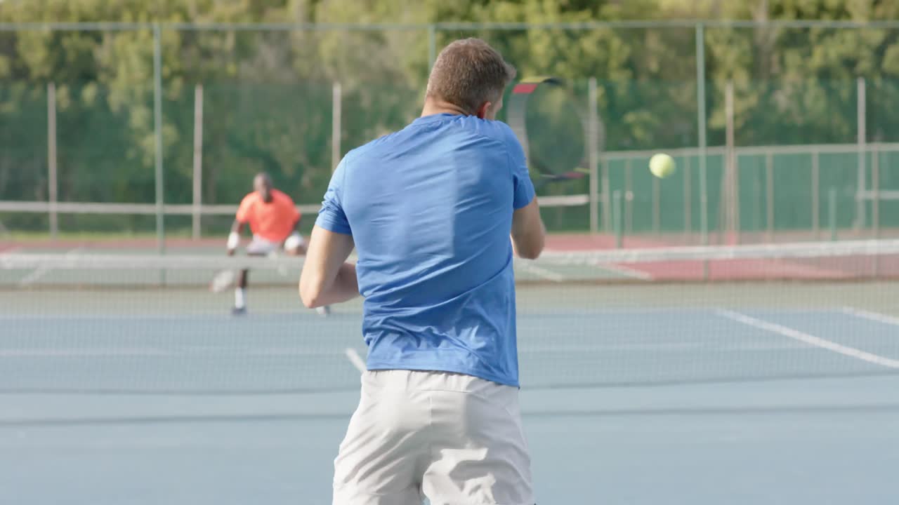 Caucasian male tennis player celebrating point against diverse opponent on court in slow motion