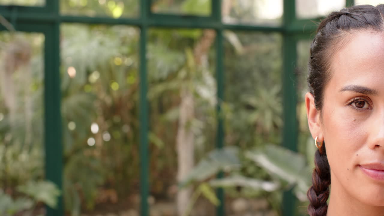 Practicing yoga, woman with braided hair in glass house, focusing on wellness, copy space