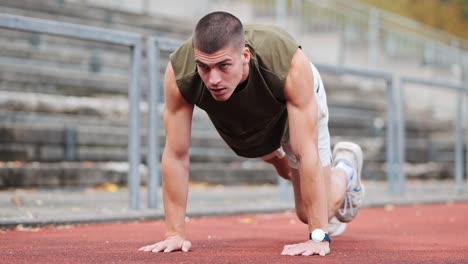 athletic sportsman training on red track of sports facility