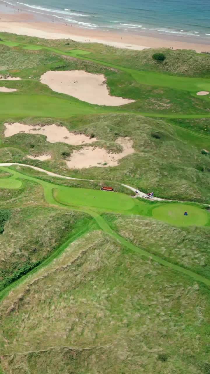 Tight reversing social ratio aerial video of Royal Portrush Golf Course in County Antrim, Northern Ireland, UK on a sunny day. Produced in 1080x1920 vertical ratio, 60FPS and with Rec709 color
