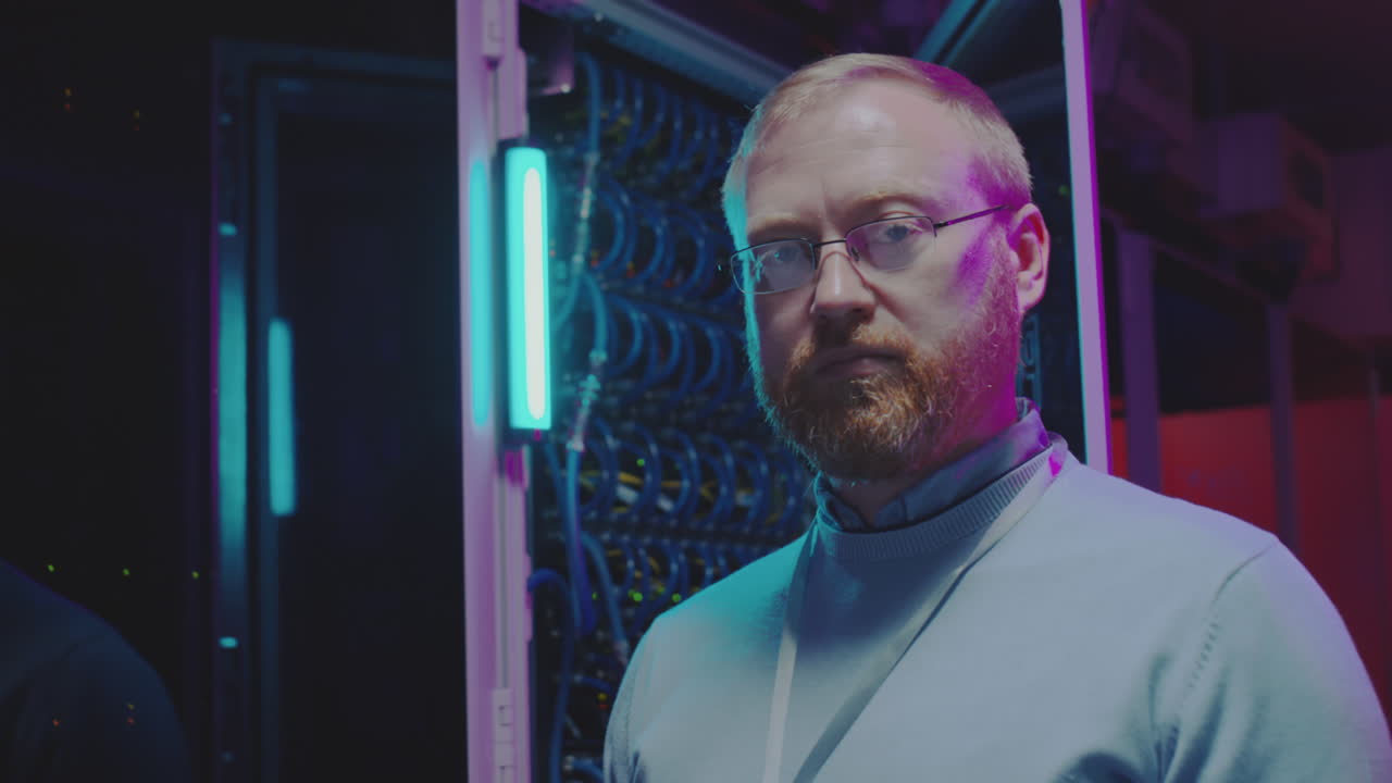 IT Professional Standing in a Server Room with Neon Lights