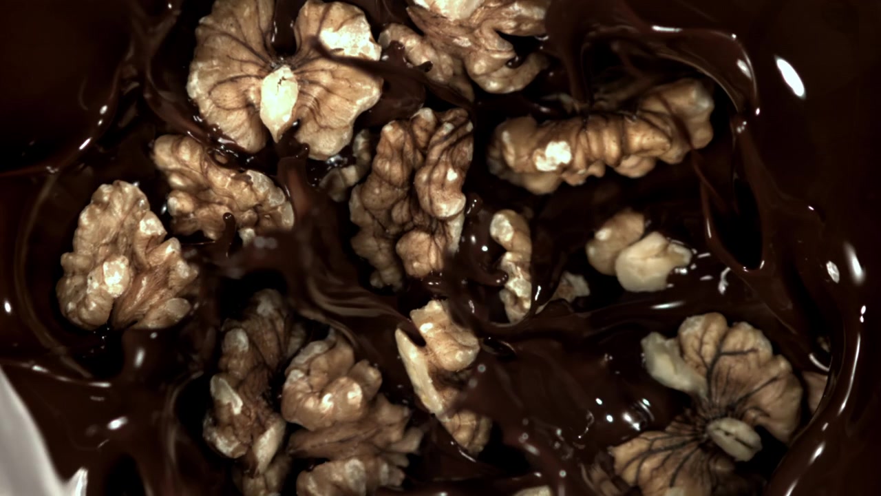 Melted Chocolate Pouring Over Walnuts in Slow Motion