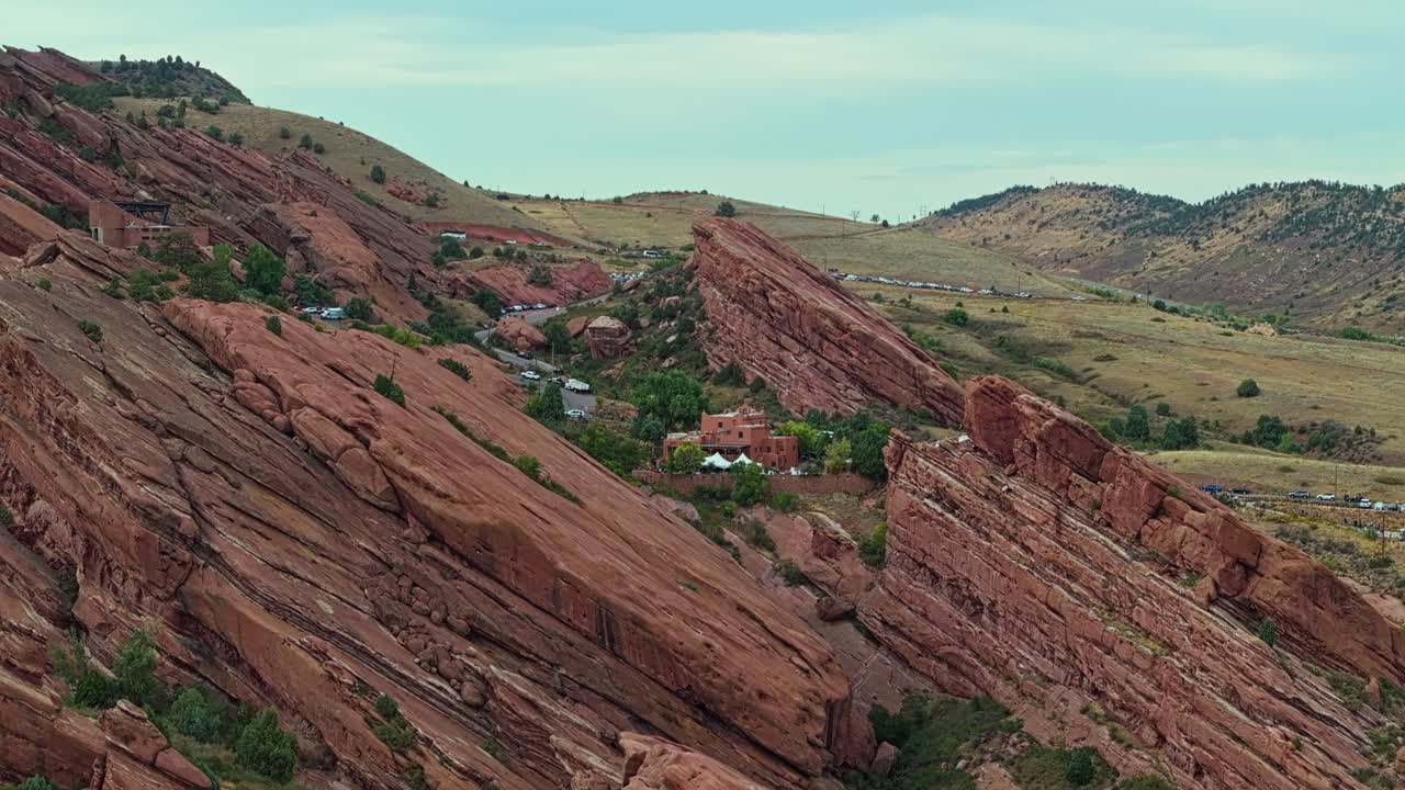 Drone ascend establish over Red Rocks Amphitheatre Colorado, layered sandstone formations and open sky