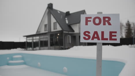 person putting for sale banner on a house