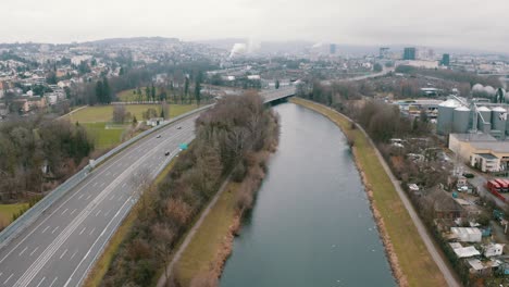 high-altitude-forward-flight-over-a-river-in-an-industrial-urban-area