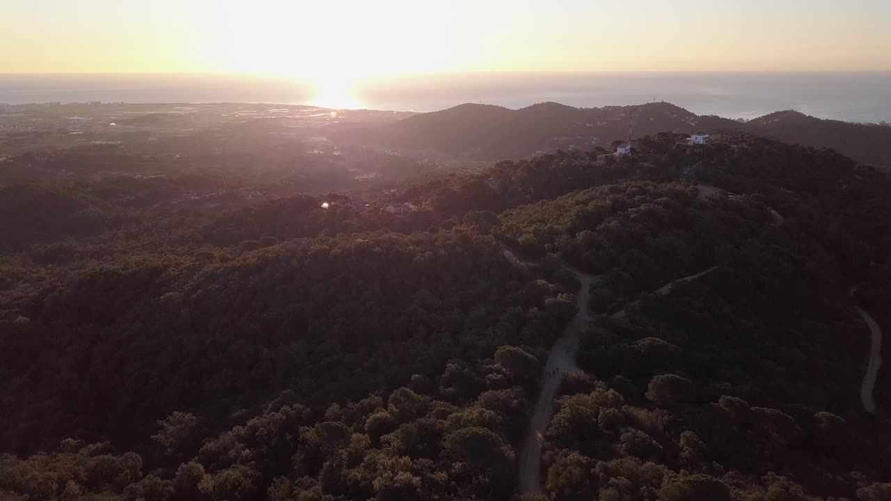 3명의 주자가 토르데라 트레일레이스의 감시탑에 접근하고, 공중 풀백 위의 수평선에 밝은 흰색 태양이 배경으로 지고 있습니다.