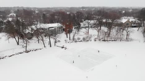 aerial of a family playing ice hockey in their backyard homemade rink while snowing