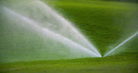 medium shot of grass sprinkler splashes water over the lawn 4