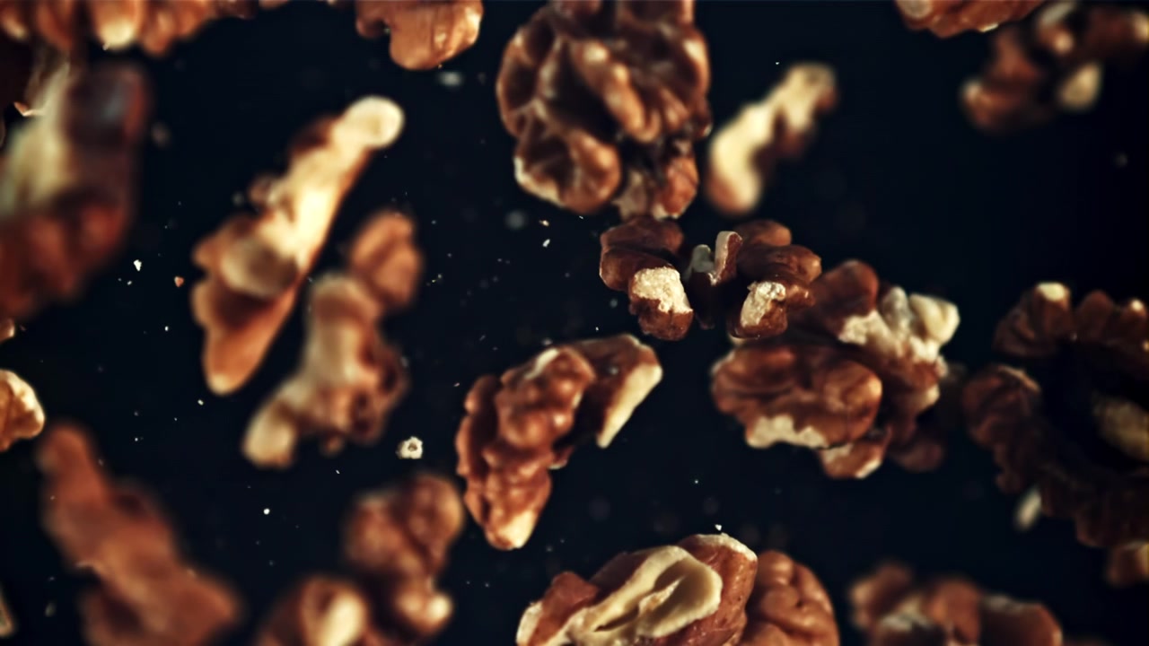 Walnut Pieces Falling in Slow Motion Against a Dark Background