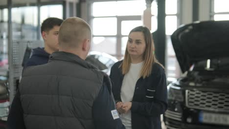 gerente femenina discutiendo la reparación de vehículos con el mecánico en el taller de reparación de automóviles