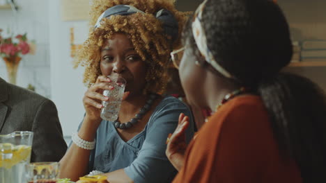 two young sisters having drinks and talking on family dinner