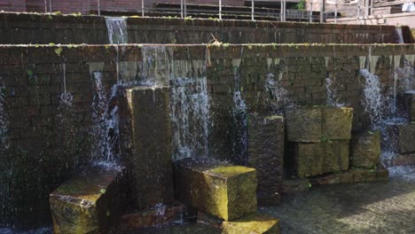 Gifu-City-Koen-Park,-Pan-across-flowing-Nagara-river-water-over-fountain