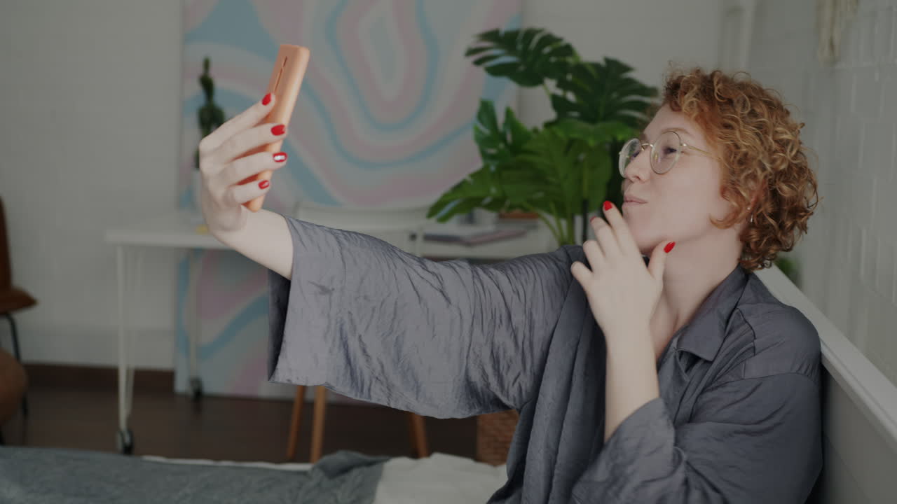 Woman taking a fun selfie on her phone while in her bedroom