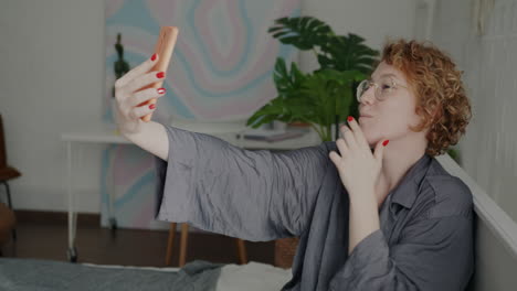 woman taking a fun selfie on her phone while in her bedroom