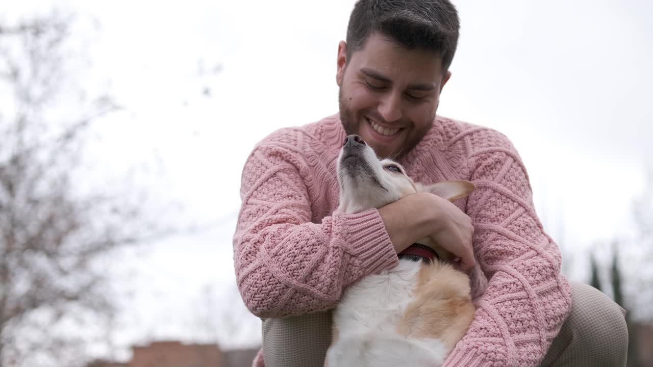 Man hugging and stroking his dog while enjoying the day outdoors in the park.