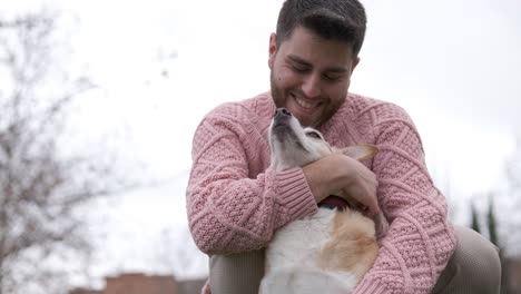 man hugging and stroking his dog while enjoying the day outdoors in the park.