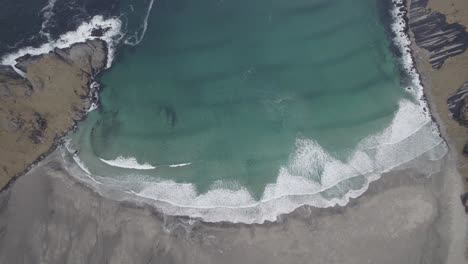 aerial view above waves crashing a beach, in lofoten, norway - birds eye, drone shot