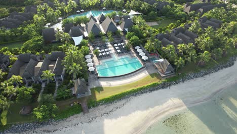 aerial descends over oceanfront tropical luxury resort pools at natadola beach, fiji