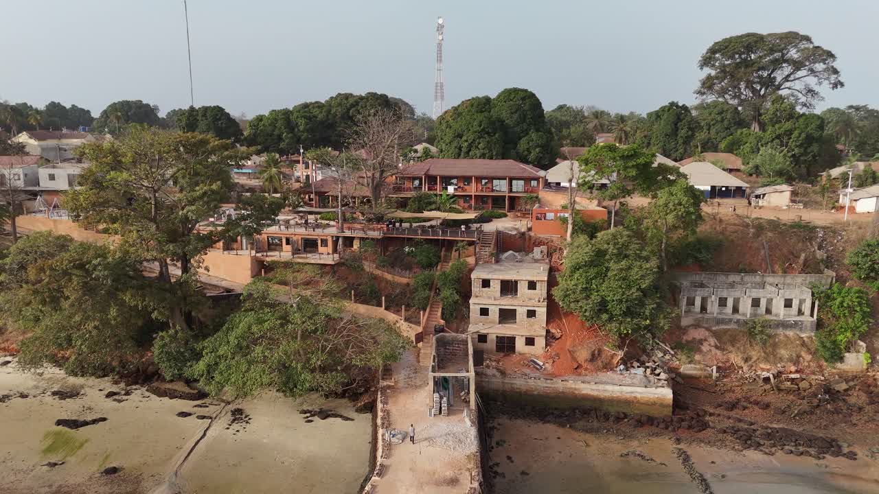 Aerial footage of resort buildings under construction in Bijagos Islands, surrounded by tropical forest and natural landscape