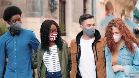 grupo de amigos multiétnicos con máscara y caminando por la calle