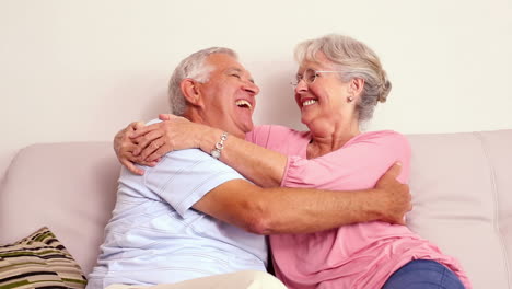 Senior-couple-sitting-on-sofa-hugging