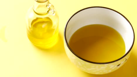cuenco amarillo de aceite de oliva sobre fondo amarillo