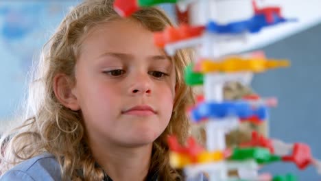 bonita colegiala caucásica estudiando el modelo de adn en el aula en la escuela 4k