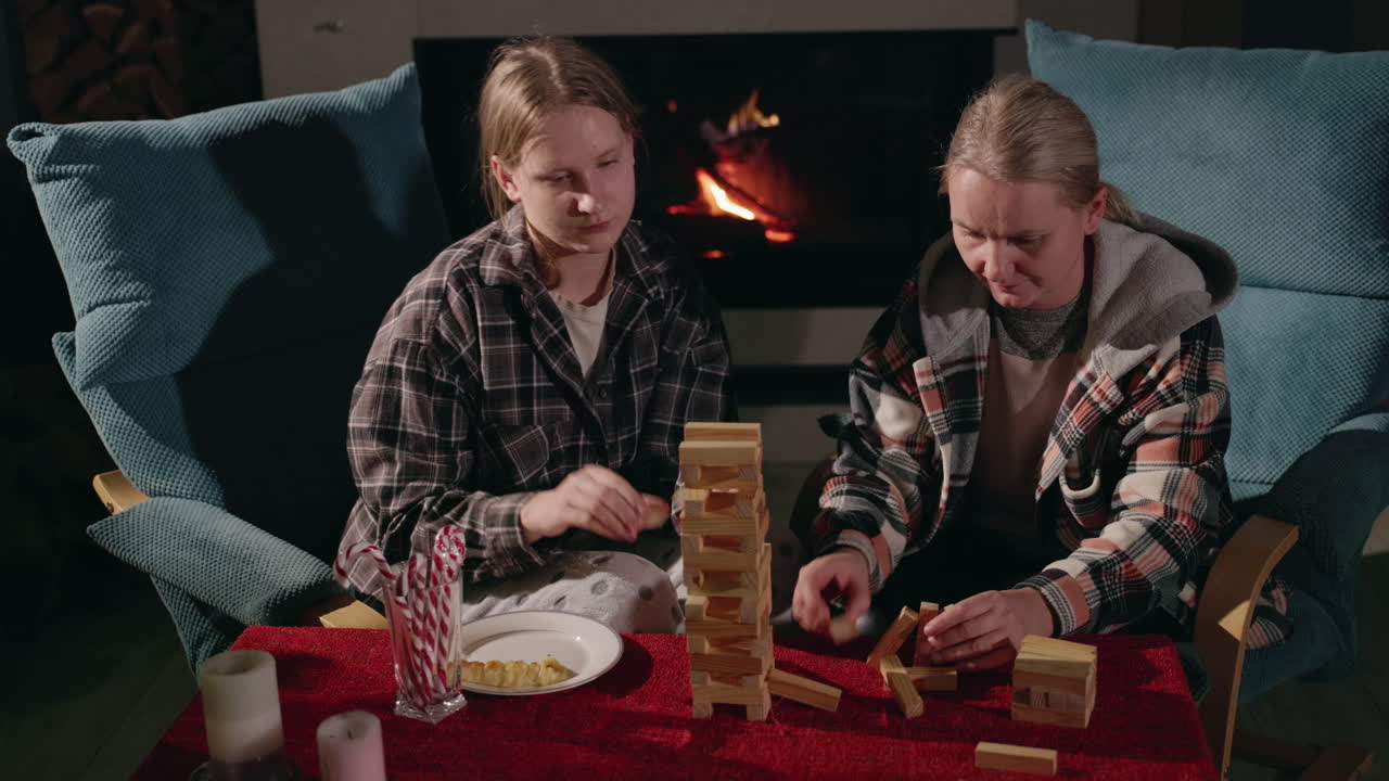 Sisters playing Jenga at home by the fireplace