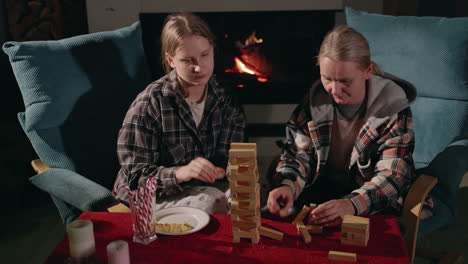 sisters playing jenga at home by the fireplace