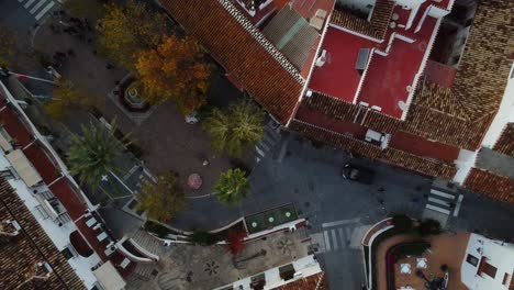 Narrow-street,-red-rooftops-and-white-buildings-of-Mijas,-aerial-top-down-view