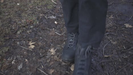 a person wearing black shoes walking on the messy and muddy walkway