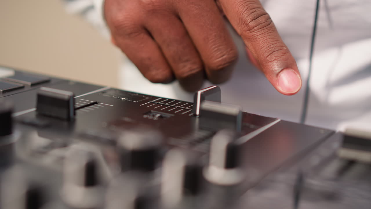 closeup black DJ adjusting mixer knob, studio producer finetuning levels and EQ, focused engineer workflow, headphones on monitors, sample editing and arrangement, calm creative atmosphere, remix
