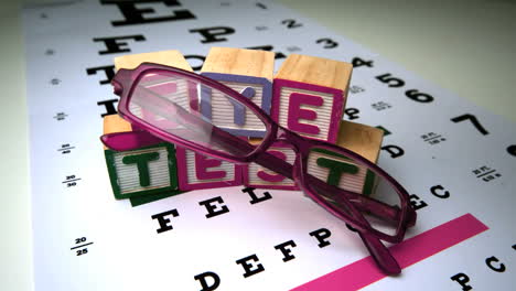 pink glasses falling next to blocks spelling out eye test