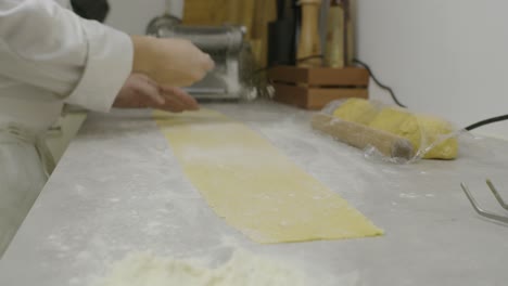 chef adds flour onto the pasta dough on the kitchen table