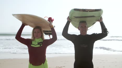 middle aged surfers walking on sandy beach