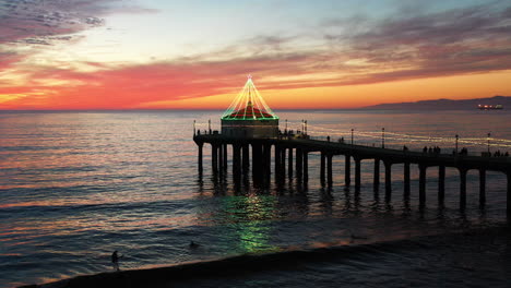 vista aérea del muelle de manhattan beach brillando con luces navideñas, california, al atardecer