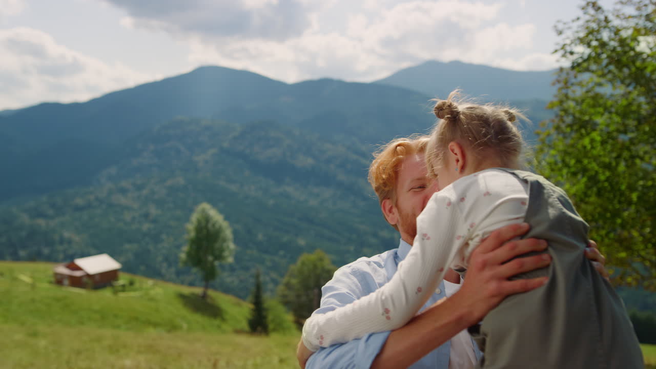 Primo piano di padre che solleva la figlia in una valle di montagna. Uomo che fa girare la bambina.