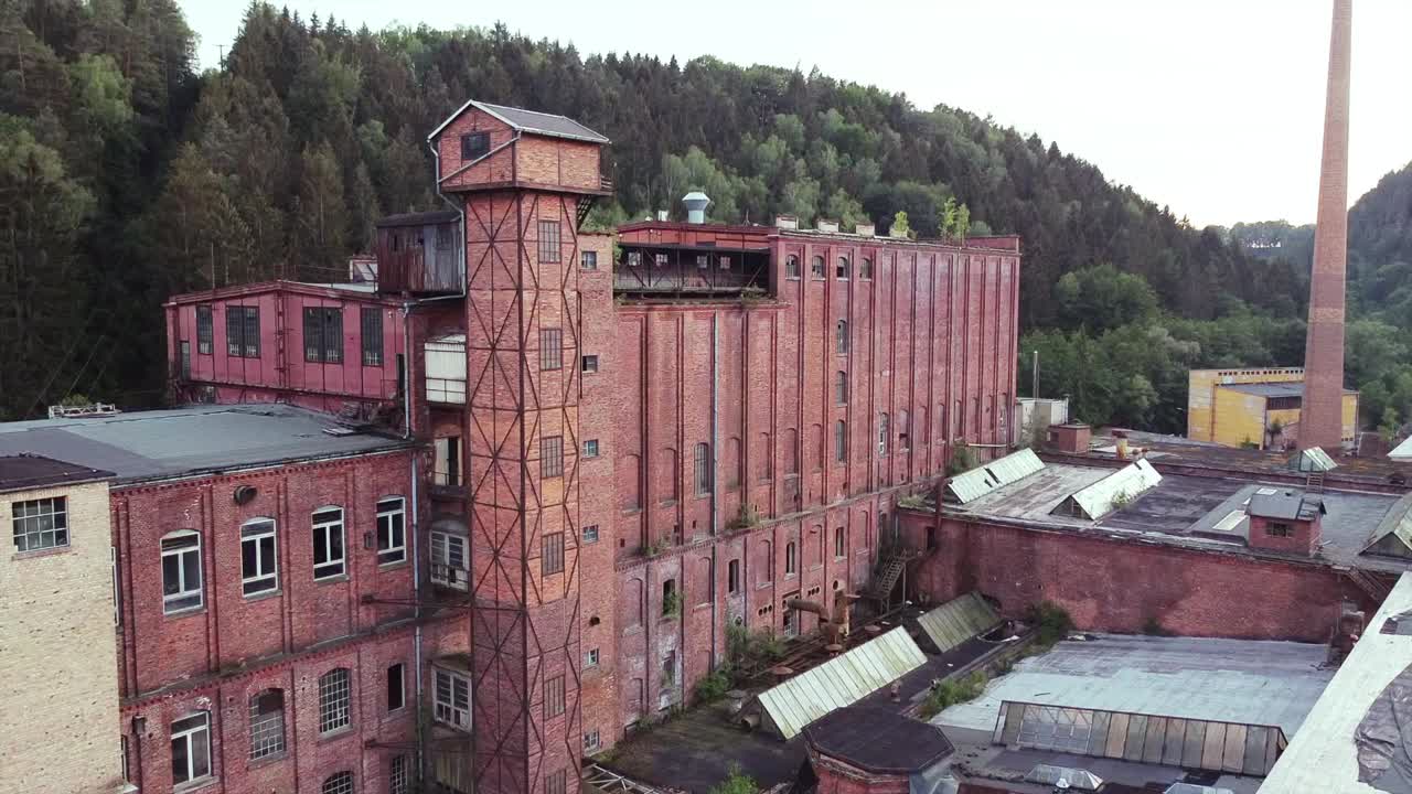 Drone descending with view on a socialist factory abandoned in the middle of nowhere in the evening light
