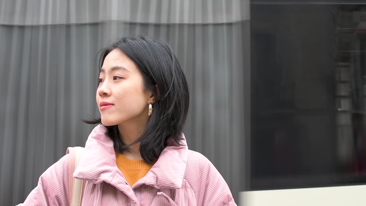 자동차가 그녀의 뒤를 지날 때 거리에서 앞뒤로 보고 있는 아시아 소녀