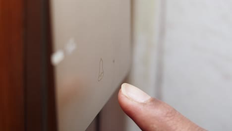 el dedo presionando un botón del timbre