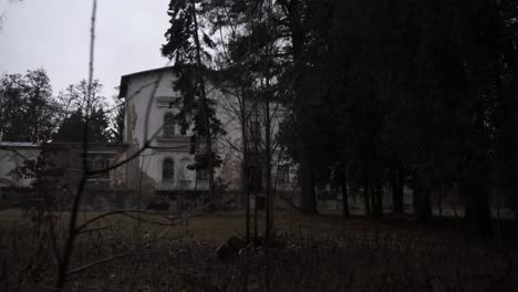 Eye-level-view-over-an-old-abandoned-mansion-covers-the-trees,-dark-colours-concept,-camera-side-shot