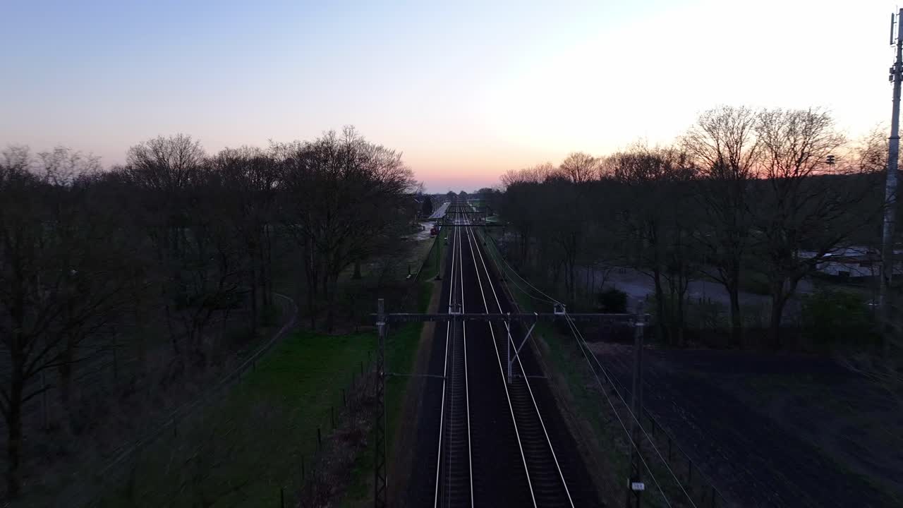 Overview drone view of the railroad tracks stretching into the horizon in rural dusk scenery.