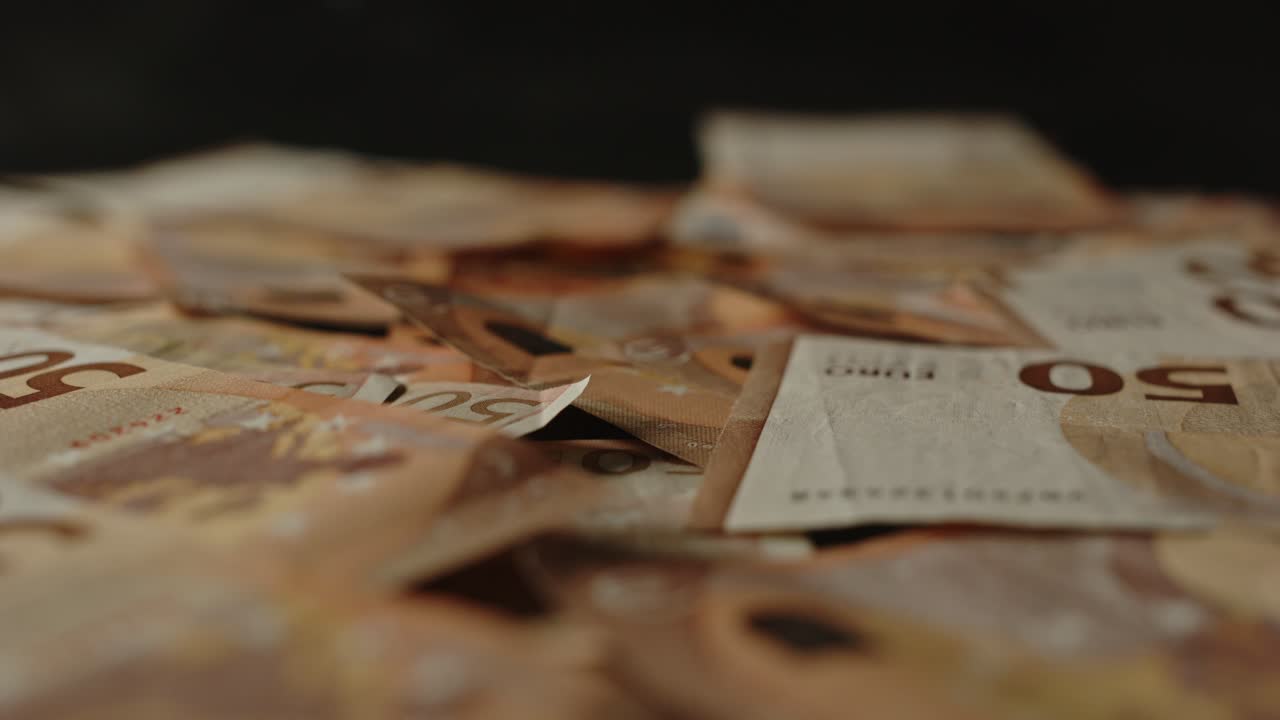 Kameraet dollyer ind på flere 50 euro-sedler på en sort overflade.