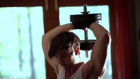 tight shot of a teen bodybuilder doing a military press or tricep extension behind his head with a heavy group of weights